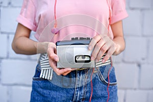 cropped shot of woman with earphones holding retro cassette player in hands against white