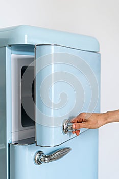 Cropped shot of woman hand hold handle and open door of freezer compartment