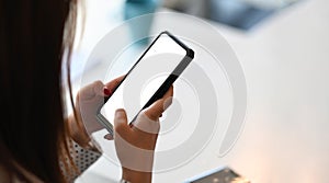 Cropped shot of woman hands are holding and touch a black cell phone with white blank screen.