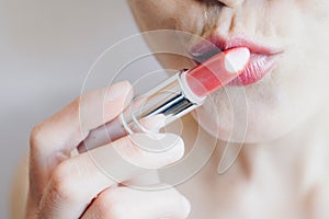 Cropped shot of woman holding and kiss a lipstick and applying on her lips.