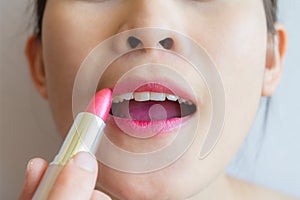 Cropped shot of woman holding a lipstick and applying on her lips.