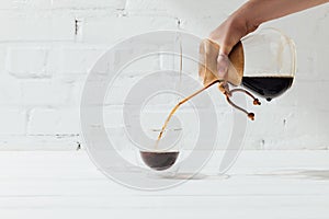 Cropped shot of woman pouring alternative coffee from chemex into glass mug