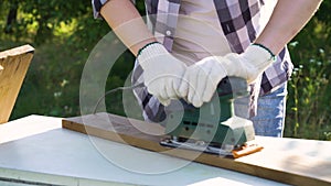 Cropped shot of woman in protective gloves polishing plank with electric sander
