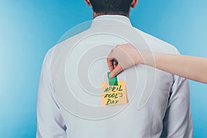 cropped shot of woman putting note with april fools day lettering on males back, april fools