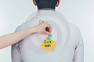 cropped shot of woman putting note with kick me lettering on males back, 1 april holiday concept photo