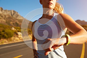 Cropped shot of woman running and checking her sports watch