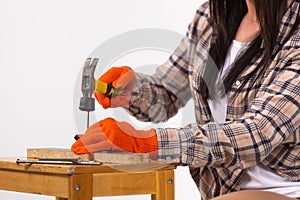 Cropped shot of a woman`s hands hammering a nail on white. Gender stereotypes