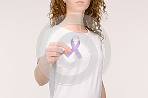 cropped shot of woman showing purple awareness ribbon for general cancer awareness, Lupus awareness, drug overdose, domestic