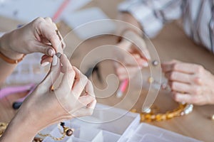 cropped shot of women making accessories of beads