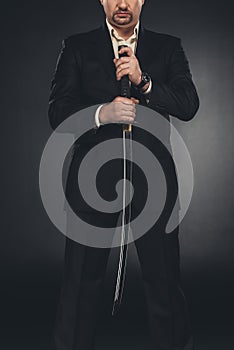 cropped shot of yakuza member in suit holding katana sword