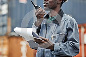 Cropped shot of young black man using walkie talkie at shipping docks