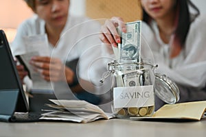 Cropped shot of young couple putting money into savings jars and planning retirement finances