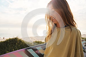 Cropped Shot Of Young Female Adventurer At The Beach Walking Down Sand Dunes With Surf Board Or Kite Surfing Sunset