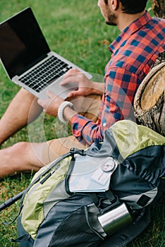 cropped shot of young male traveler using laptop