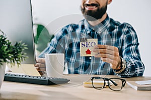 cropped shot of young smiling bearded developer holding sticker