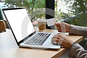 Cropped shot young woman holding credit card making purchase on laptop computer