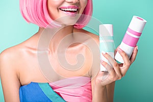 cropped shot of young woman with pink bob cut holding cans of coloring hair sprays