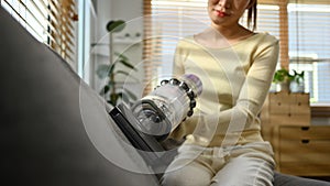 Cropped shot of young woman using handheld cordless vacuum cleaner to vacuuming and cleaning the dust on couch