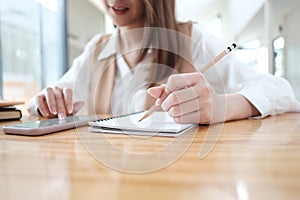 Cropped shot of young woman using smart phone and preparing note for the exam.