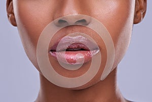 Lucious lips. Cropped shot of a young womans mouth against a purple background.