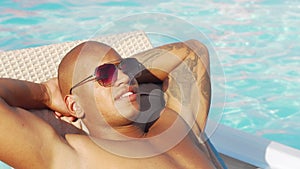 Cropped sliding shot of a happy African man relaxing at the poolside