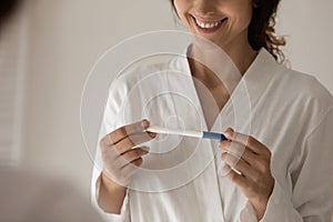 Cropped smiling young woman holding quick pregnancy test.