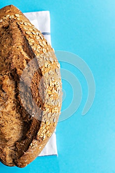 Cropped sourdough bread with oats. Blue background and copy space