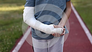 cropped video of little boy with broken hand outdoors on sports ground on summer day. 9 years child with a fractured