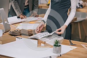 cropped view of architect reading book at workplace