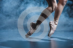 cropped view of ballerina dancing in pointe shoes in dark studio