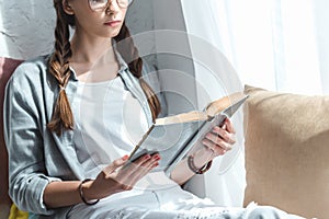 cropped view of beautiful girl reading book