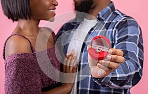 Cropped view of black couple holding box with engagement ring on pink studio background, panorama
