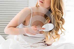 cropped view of blonde girl combing hair