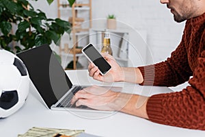 cropped view of bookmaker with smartphone