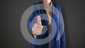 Cropped view of business woman shows thumb up. Expresses satisfaction or agreement. Isolated on gray background