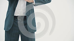 Cropped view of businessman in dark suit and blue tie putting his hands in pockets over white background.