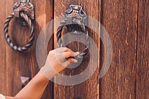 cropped view of child knocking in door with metal handle