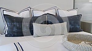 Cropped view of decorative pillows combination laying on white blanket on top of large bed. Sophisticated furniture with