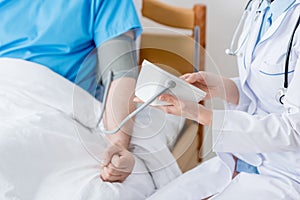 cropped view of doctor measuring blood pressure of patient in hospital.