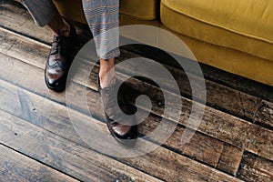 cropped view of elegant stylish man in brogue shoes standing at sofa
