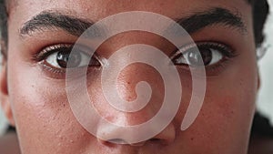 Cropped view of a face portrait of a young multiethnic woman looking at the camera with a sad look. Focus on female eyes