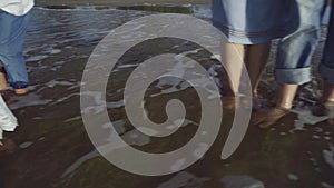 Cropped view of family legs standing barefoot in sea on beach.Summer family holidays, vacation concept