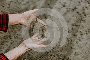 Cropped view of farmer hands pouring dry sandy soil