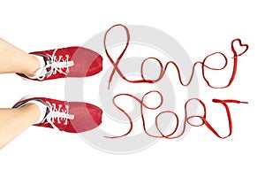 Cropped view of female feet wearing red running sneakers and lettering `love sport` made of athletic shoelaces isolated on white