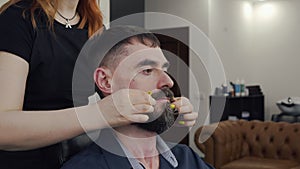 Cropped view of female hairdresser twisting moustaches of client