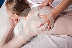 Young woman taking pleasure on massage bed, with eyes closed. Woman. Spa salon.