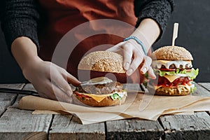 cropped view of girl in apron making homemade cheeseburgers on baking paper