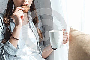 cropped view of girl eating cookie