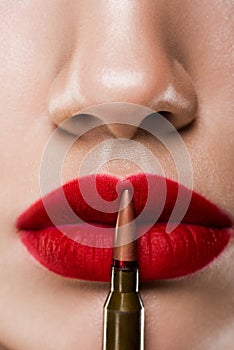 cropped view of girl holding bullet near red lips