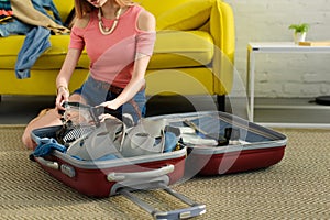 cropped view of girl packing goggles and snorkeling fins into suitcase